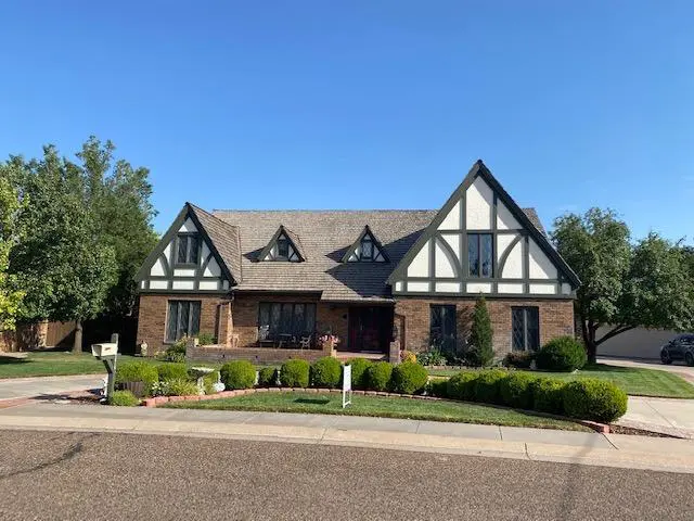 Large Tudor style home with high peaks and lots of stonework, along with a nice, green lawn